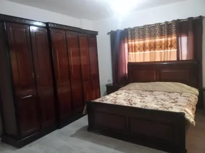 a bedroom with a bed and wooden cabinets at بوابة جرش الرومانيه الشماليه in Jerash