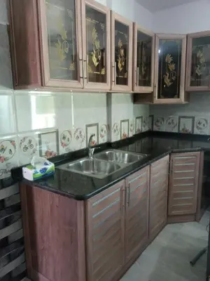 a kitchen with a sink and wooden cabinets at بوابة جرش الرومانيه الشماليه in Jerash