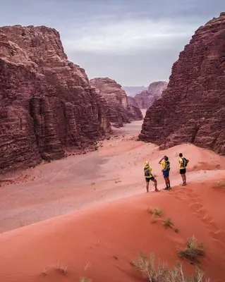 three people walking through the desert in a canyon at WADi RUM HiLTON lUXURY BUBBLE CAMP in Disah