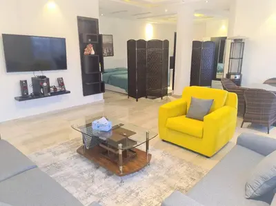 a living room with a yellow chair and a table at Khalda Rooftop Apt. in Amman
