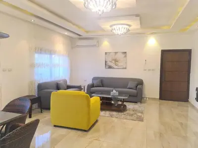 a living room with two couches and a yellow chair at Khalda Rooftop Apt. in Amman