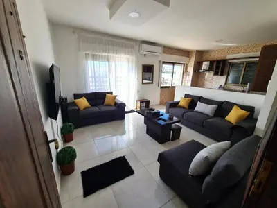 a living room with two couches and a tv at Khalda Rooftop Apt. in Amman