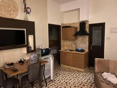 a kitchen and living room with a table and a television at Mesha Stele Private Hotel in Madaba