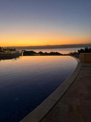 a pool of water with a sunset in the background at Apartment at Samarah Dead Sea Resort APT D-09 in Sowayma
