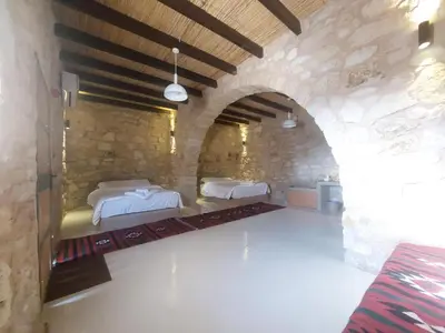 a bedroom with two beds in a stone wall at Tafileh-Sila'a Heritage Village in At-Tafilah