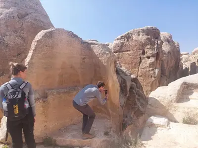 a man taking a picture of a person standing on a rock at Tafileh-Sila'a Heritage Village in At-Tafilah