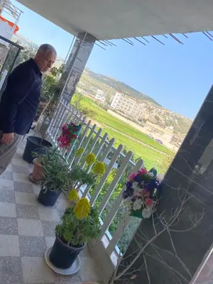 a man standing on a balcony with potted plants at huseein rooms in Jerash