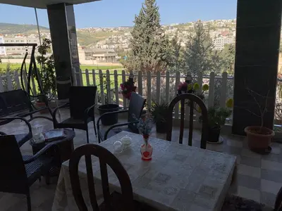 a table and chairs on a patio with a view at huseein rooms in Jerash