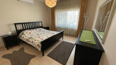 a bedroom with a bed and a table and a mirror at Abdoun Apartment in Amman