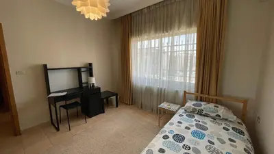 a bedroom with a bed and a desk and a window at Abdoun Apartment in Amman