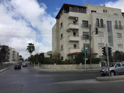a building on the corner of a street with cars at Abdoun Apartment in Amman
