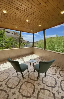 a patio with chairs and a table and a wooden ceiling at Fragrant Rose in Wadi Musa