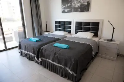 two beds in a bedroom with two blue towels on them at Sunset apartment in Samarah Dead Sea resort in Sowayma