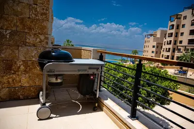 a grill on a balcony with a view of the ocean at Sunset apartment in Samarah Dead Sea resort in Sowayma