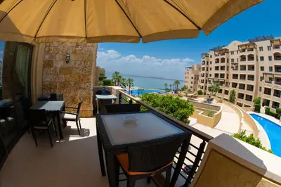 a balcony with a table and chairs and an umbrella at Sunset apartment in Samarah Dead Sea resort in Sowayma