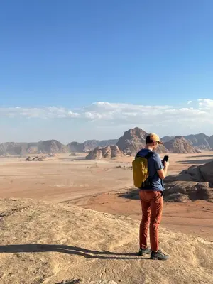 a man with a backpack taking a picture of the desert at Full moon camp in Wadi Rum