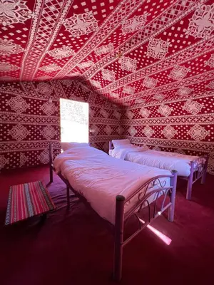 two beds in a room with red wallpaper at Wadi Rum Best Tours in Wadi Rum
