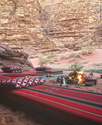a bed in the desert with a camp fire at Wadi Rum Best Tours in Wadi Rum