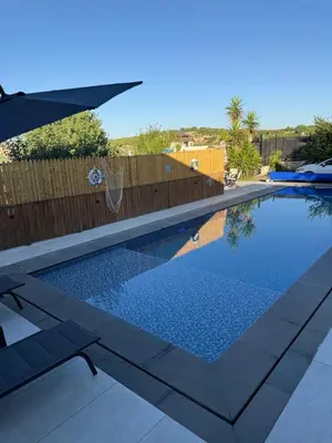 a swimming pool in a backyard with a wooden fence at Oak Farm Ajloun مزرعة البلوط عجلون in Ajloun