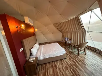 a bedroom in a tent with a bed and a table at Lulua luxury camp in Wadi Rum