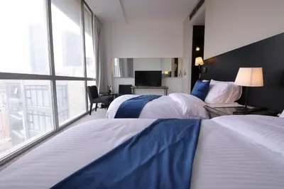 two beds in a hotel room with a large window at Boho Boutique Hotel Amman in Amman