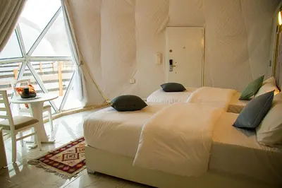two beds in a room with a large window at Desert Season Luxury Camp Wadi Rum Boutique Tents & Stargazing in Wadi Rum