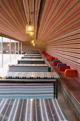 a row of benches with red and blue seats at Desert Season Luxury Camp Wadi Rum Boutique Tents & Stargazing in Wadi Rum