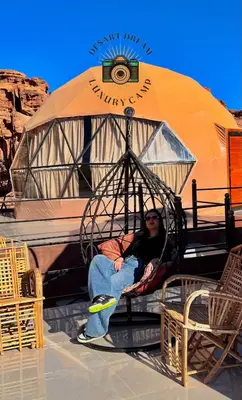 a man sitting on a swing in front of a tent at RUM DREAM BUBBLES lUXURY CAMP in Wadi Rum