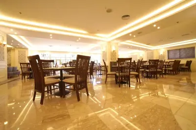 a restaurant with wooden tables and chairs in a room at Amman Paradise Hotel in Amman