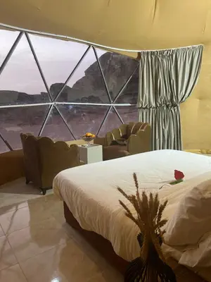 a bedroom with a bed and chairs and a large window at Queen's Magic Camp in Wadi Rum