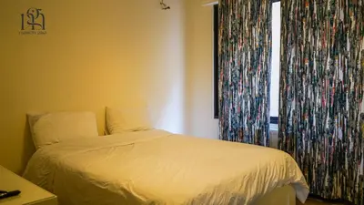 a bedroom with a bed and a window with curtains at Maison Gaia, A Stylish Apartment in the heart of Amman in Amman