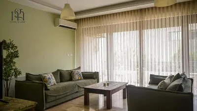 a living room with a couch and a table at Maison Gaia, A Stylish Apartment in the heart of Amman in Amman