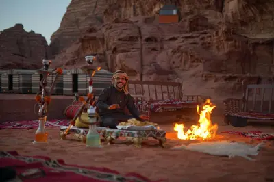 a man sitting in front of a fire at Magic Bedouin Star in Wadi Rum