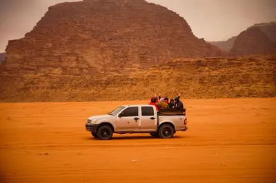 a group of people in the back of a white truck in the desert at Magic Bedouin Star in Wadi Rum