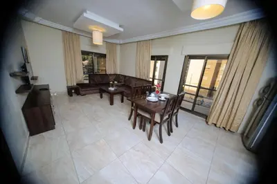a living room with a couch and a table and chairs at LANCASTER HOTEL APARTMENTS DAHIET ALRASHEED in Amman