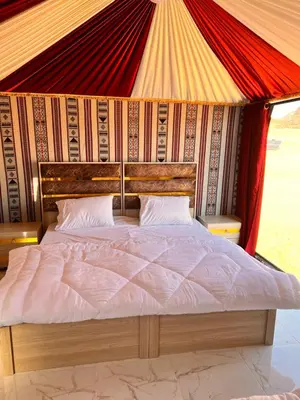 a bedroom with a bed with a red and yellow canopy at Wadi Rum Sand Camp in Disah