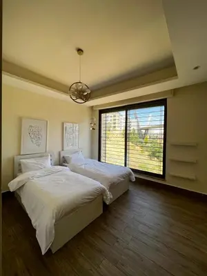 a bedroom with two beds and a large window at The bridge Residence in Amman