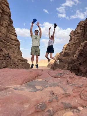 two people jumping on the rocks in the desert at Jori Luxury Camp in Wadi Rum