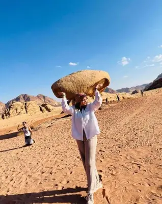 a woman in the desert holding a large mushroom on her head at Awad Bedouin camp in Wadi Rum