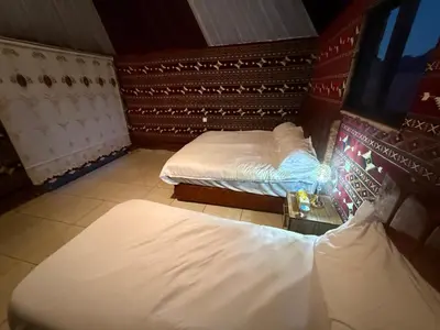 a room with two beds and a tv in it at Desert Nights Camp in Wadi Rum