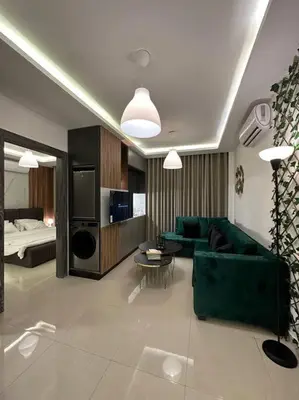 a living room with a green couch and a bed at modern apartment in abdoun-amman in Amman
