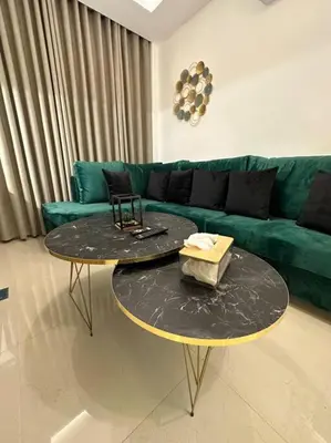 two tables in a living room with a green couch at modern apartment in abdoun-amman in Amman