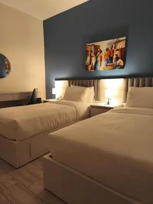 a hotel room with two beds and a painting on the wall at 46 Serviced Apartments in Amman