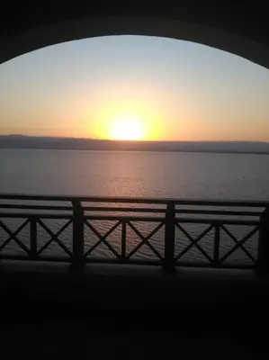 a sunset over the water from a bridge at Dead Sea Jordan Sea View Samarah Resort Traveler Award 2024 winner in Sowayma