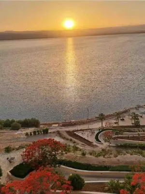 a sunset over a body of water with the sun setting at Dead Sea Jordan Sea View Samarah Resort Traveler Award 2024 winner in Sowayma