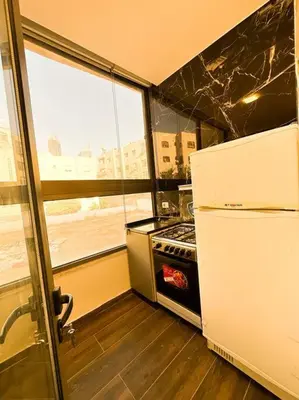 a small kitchen with a refrigerator and a stove at central apartment for rent 28 in Umm Uthainah