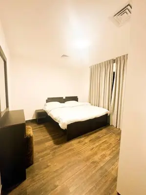 a bedroom with a bed in a room with wooden floors at central apartment for rent 25 in Umm Uthainah