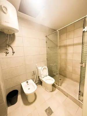 a bathroom with a toilet and a shower and a sink at central apartment for rent 27 in Umm Uthainah