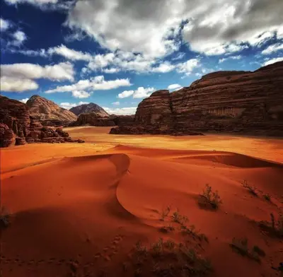 a desert with rocks and a sky with clouds at Golden sunset luxury camp in Wadi Rum