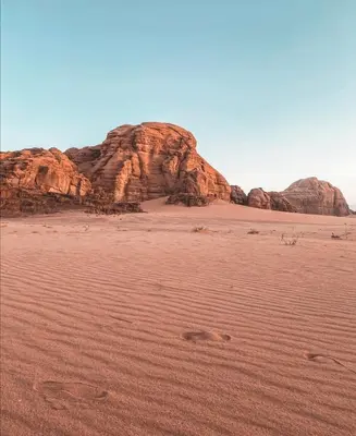 a desert with rocks and footprints in the sand at Golden sunset luxury camp in Wadi Rum
